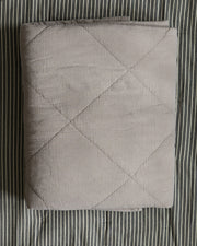 sengeteppe-beige-paa-stripet-bakgrunn