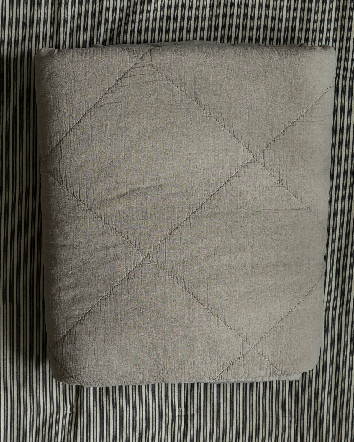 sengeteppe-paa-stripet-bakgrunn