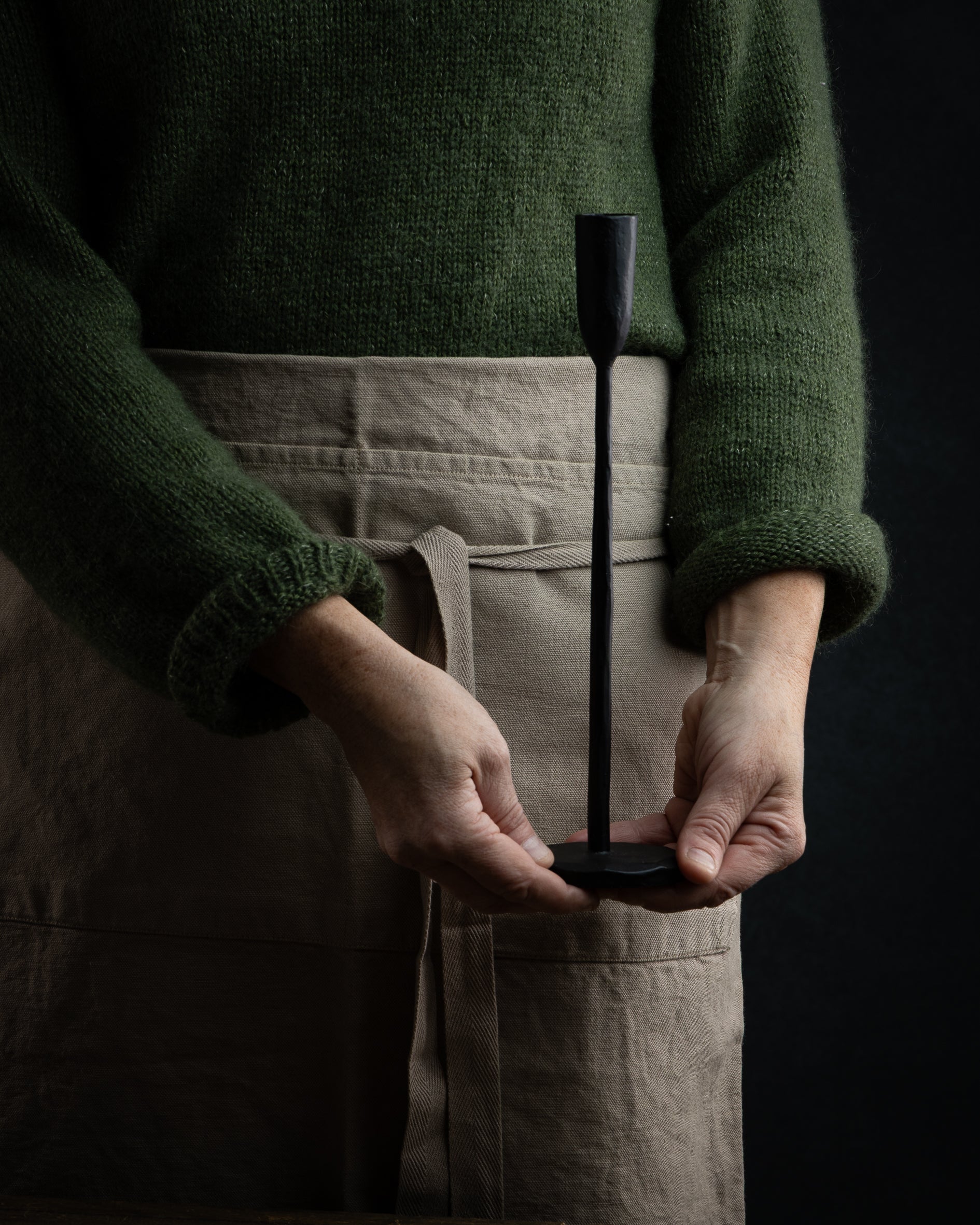 Nærbilde av hendene til en dame som holder en lysestake i smijern på 30cm