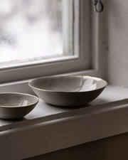 beige-skaalmed-gullkant-staaende-i-vinduskant