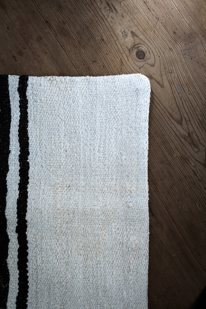 Del av et kelim putetrekk i lys beige med to brune striper 