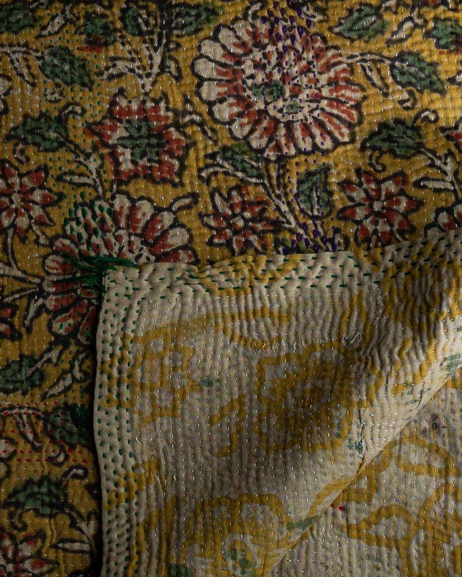 Detaljbilde av sariteppe med blomster og grunnfarge i gult 