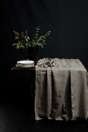 duk-naturfarget-paa-trebord-med-tallerken-og-blomst