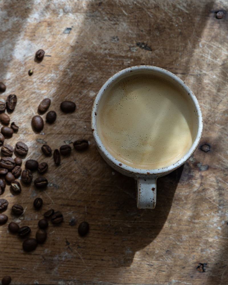 kaffekopp-med-kaffe-ved-siden-av-bonner