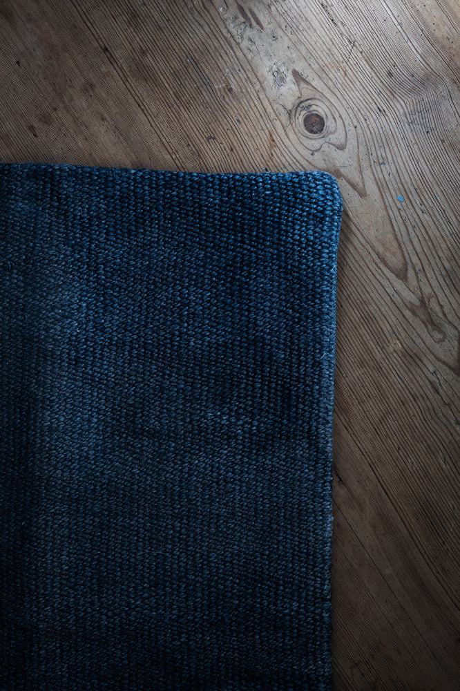 Hjørnet av et kelim putetrekk i mørk blå denim