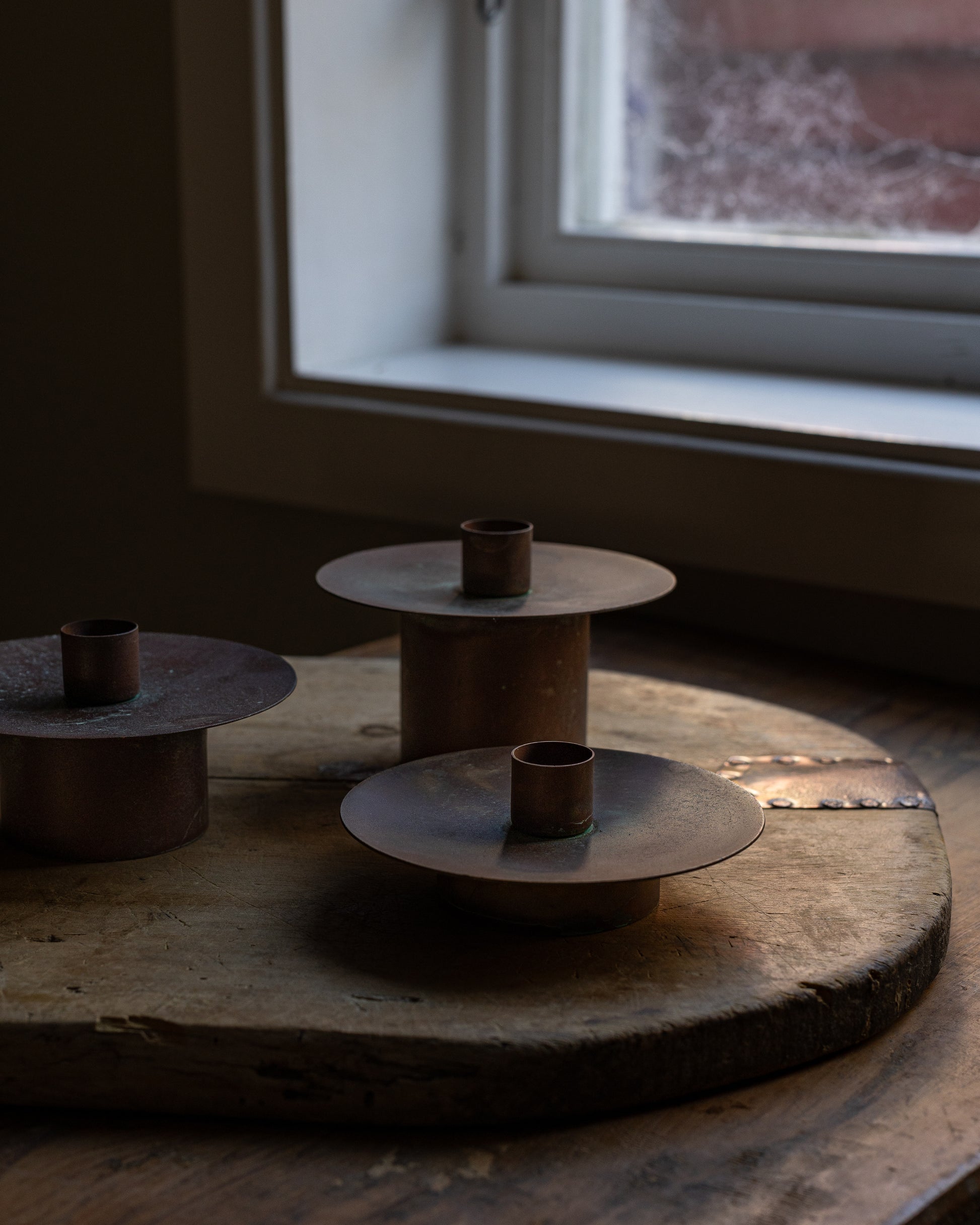 3 stk kobberlysestaker i en vinduskarm 