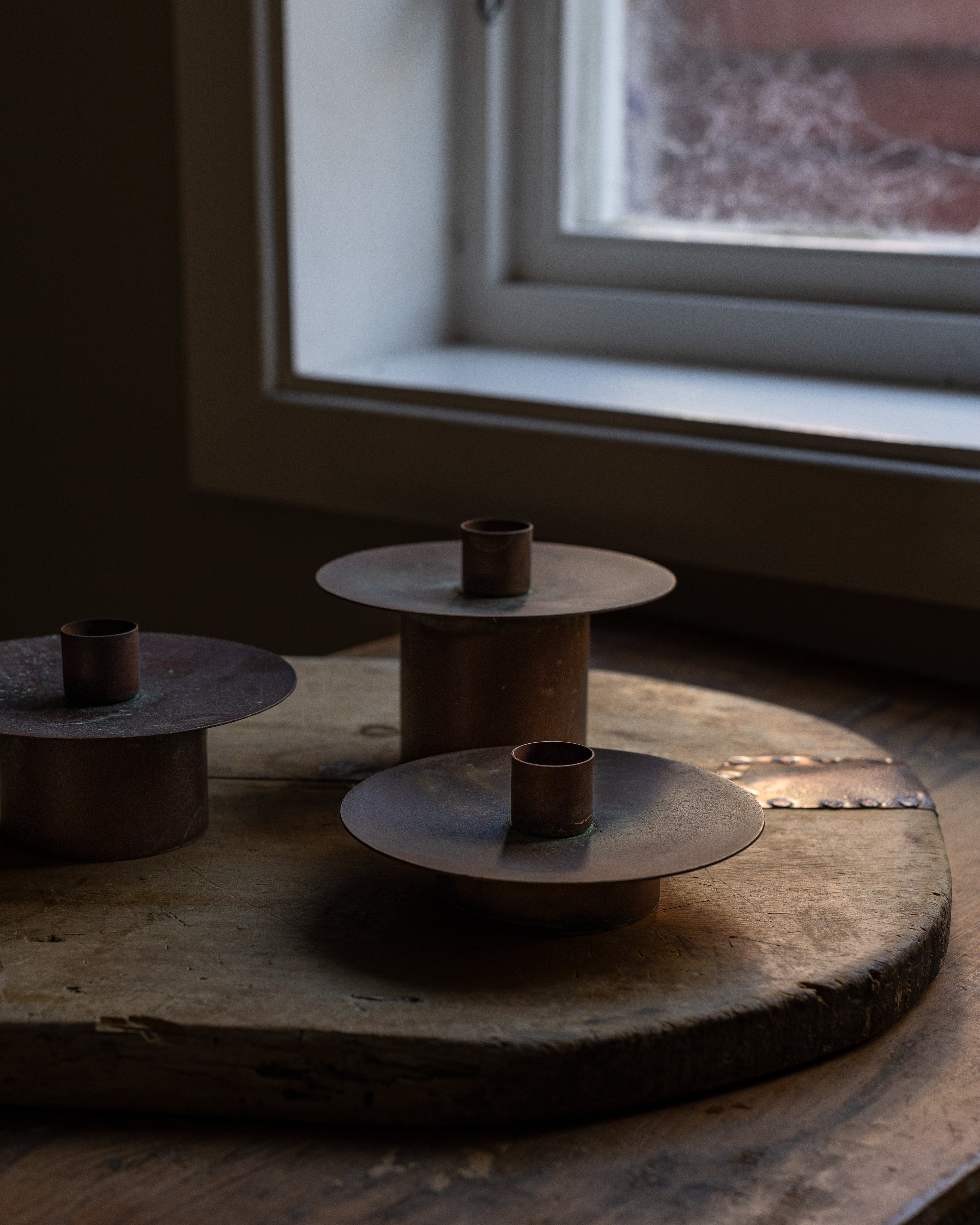 3 stk kobberlysestaker i en vinduskarm 