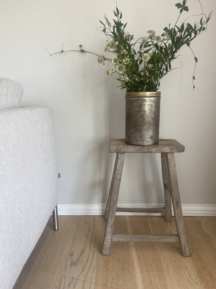 Vintage krakk i gamle materialer som blir brukt som et sidebord ved siden av en sofa