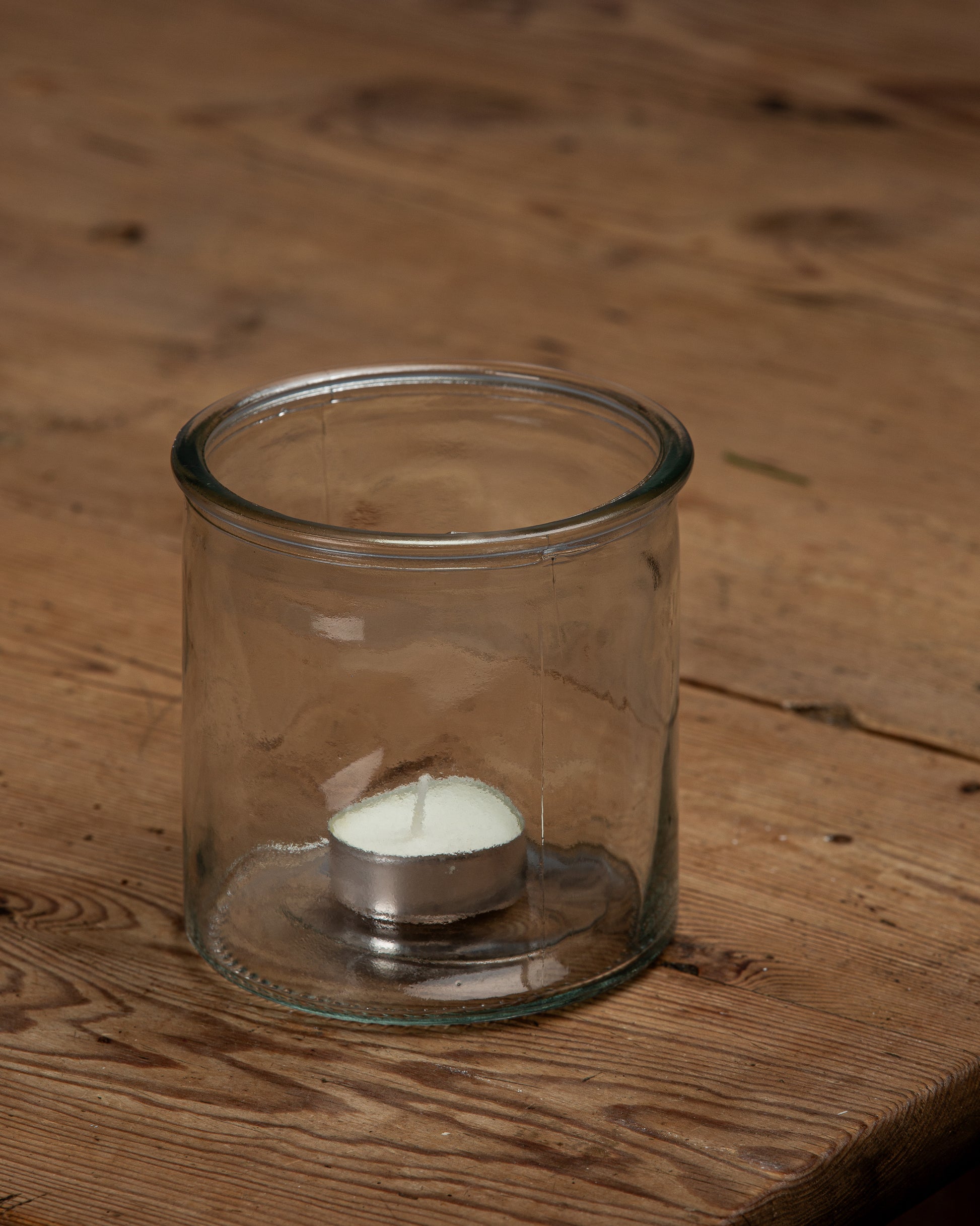 Liten rund glassvase med et telys oppi 