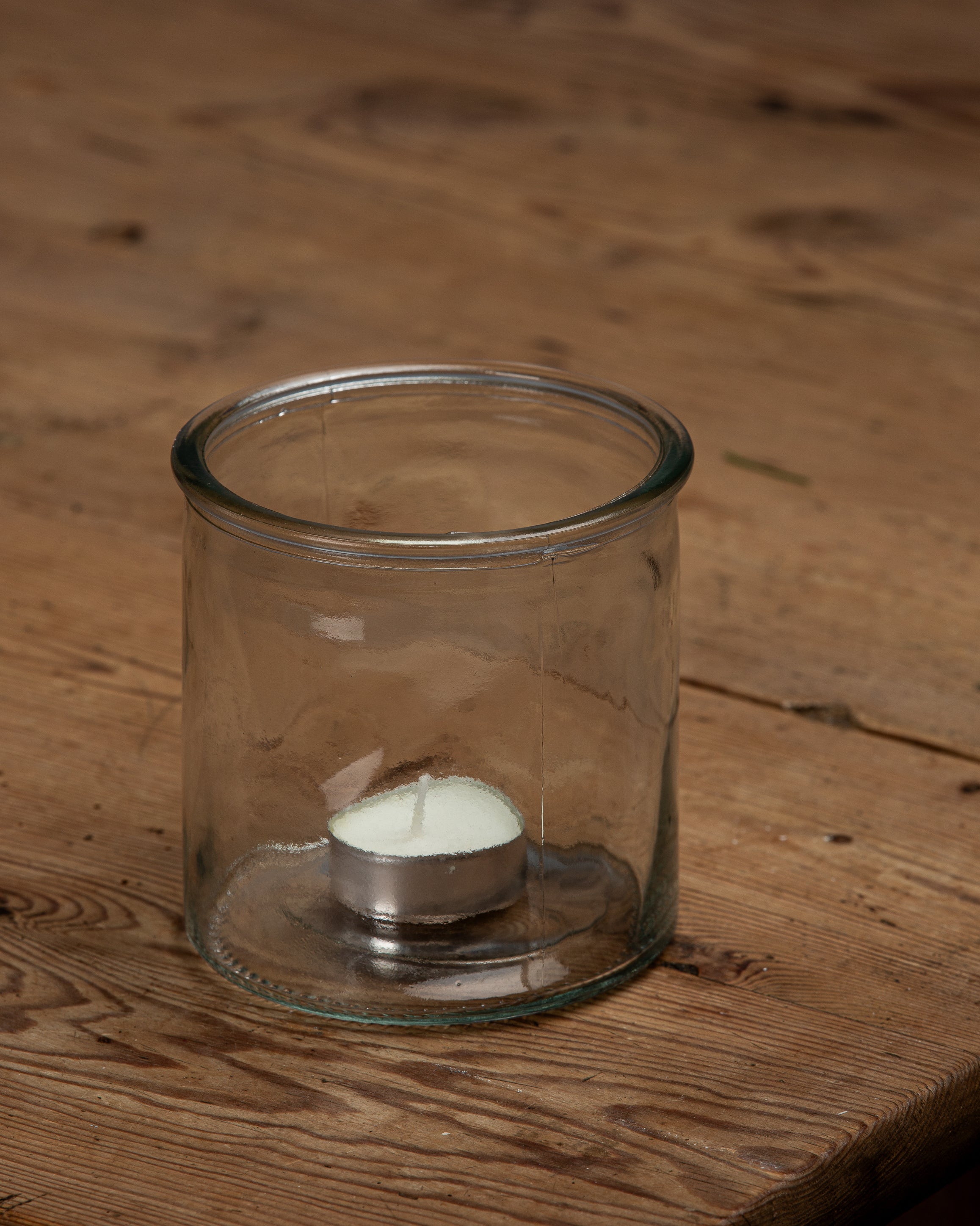 Liten rund glassvase med et telys oppi 
