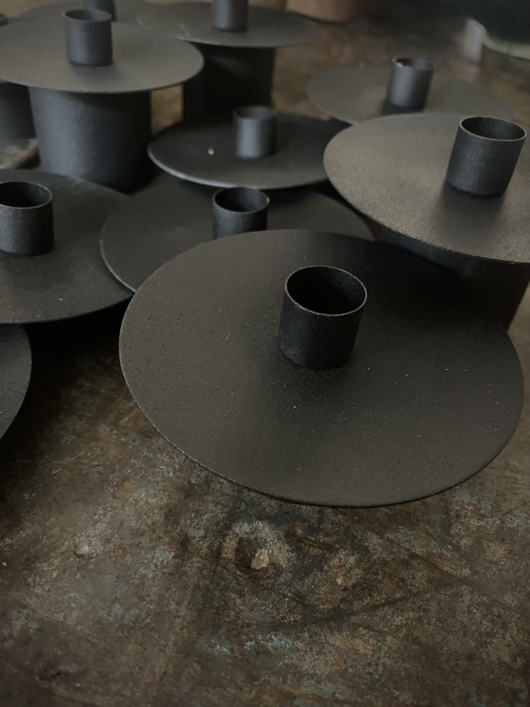 Mange lysestaker i jern samlet på et bord 