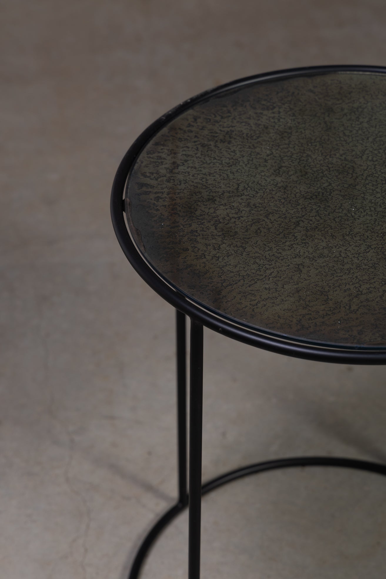 Nærbilde av antikt rundt sidebord fra Snowdrops Copenhagen med patinert bordplate og sort metallunderstell.