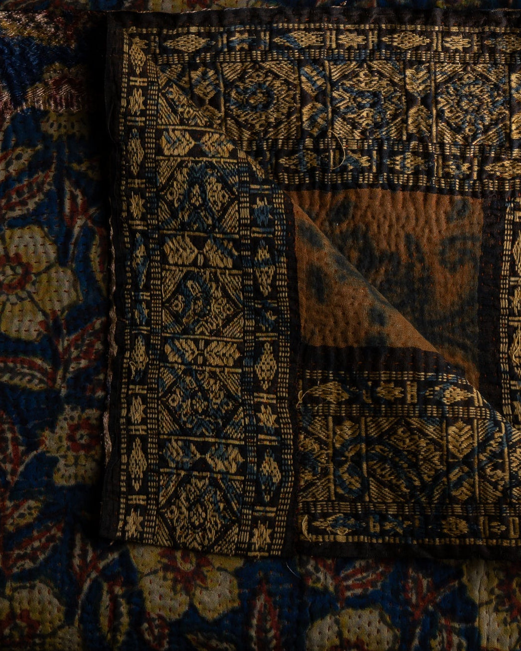 Detaljbilde av sariteppe i brente farger som brun og blå
