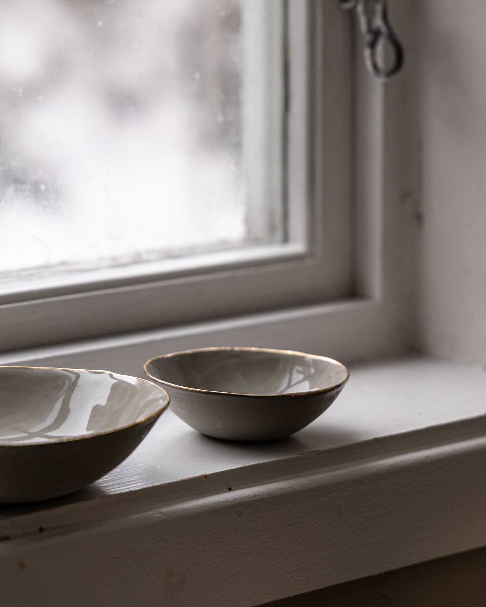 liten-skaal-beige-med-gullkant-staaende-i-vinduskarm