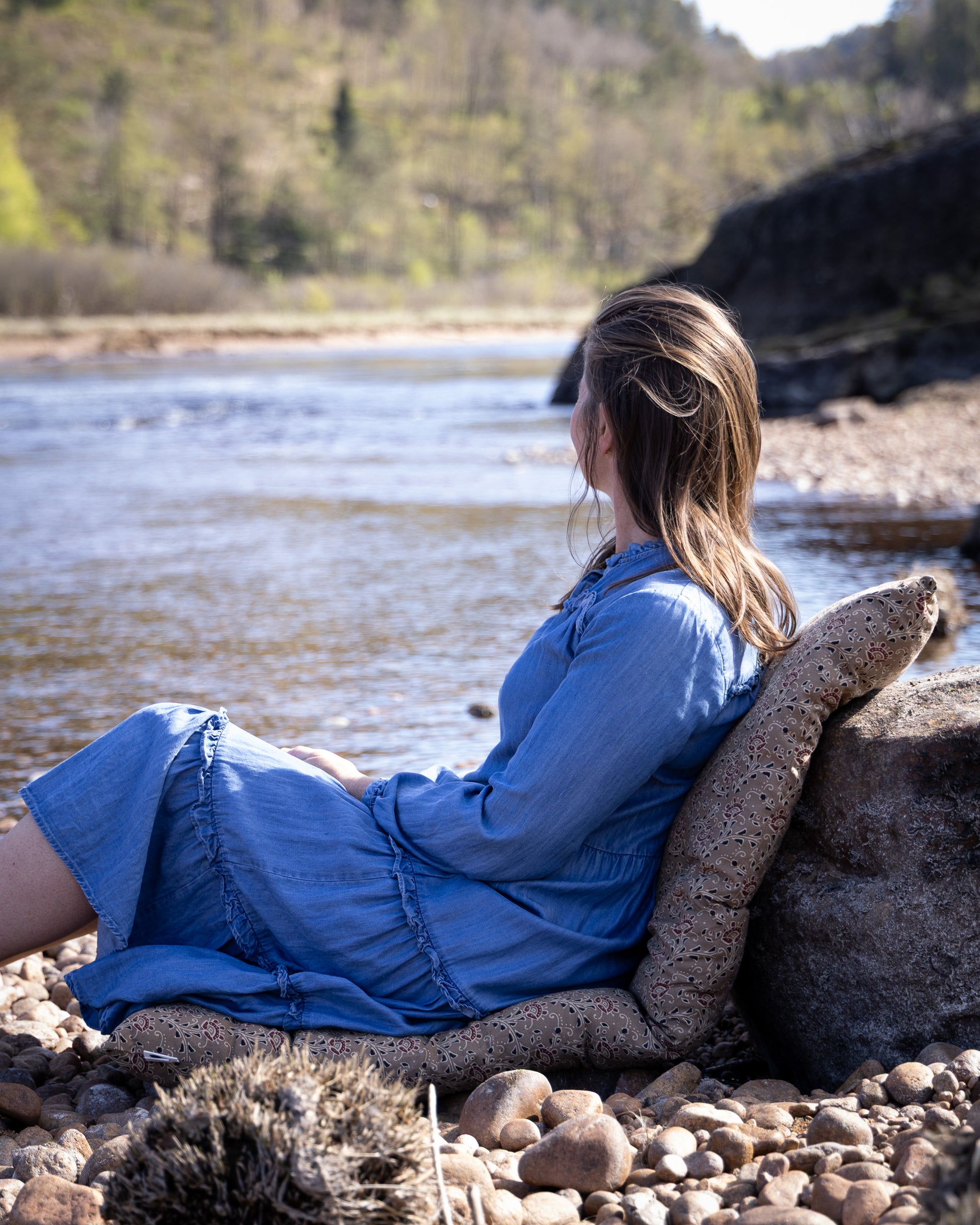 dame-som-sitter-paa-matte-pg-ser-utover-elva