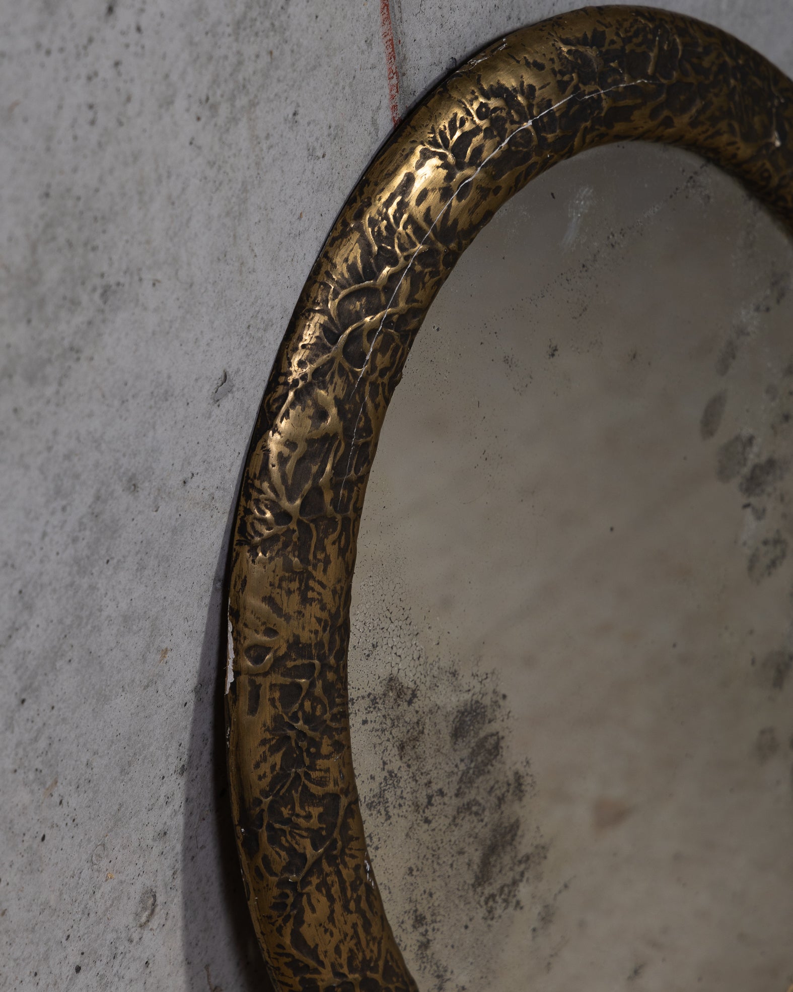 Detalbilde av et vintage rundt veggspeil med vakker patina og kraftig ramme 
